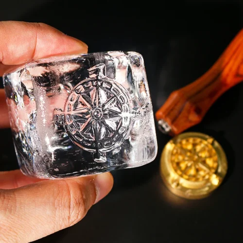 Handheld whiskey ice cube with ZHENGFEI compass imprint, made with custom brass ice stamp.