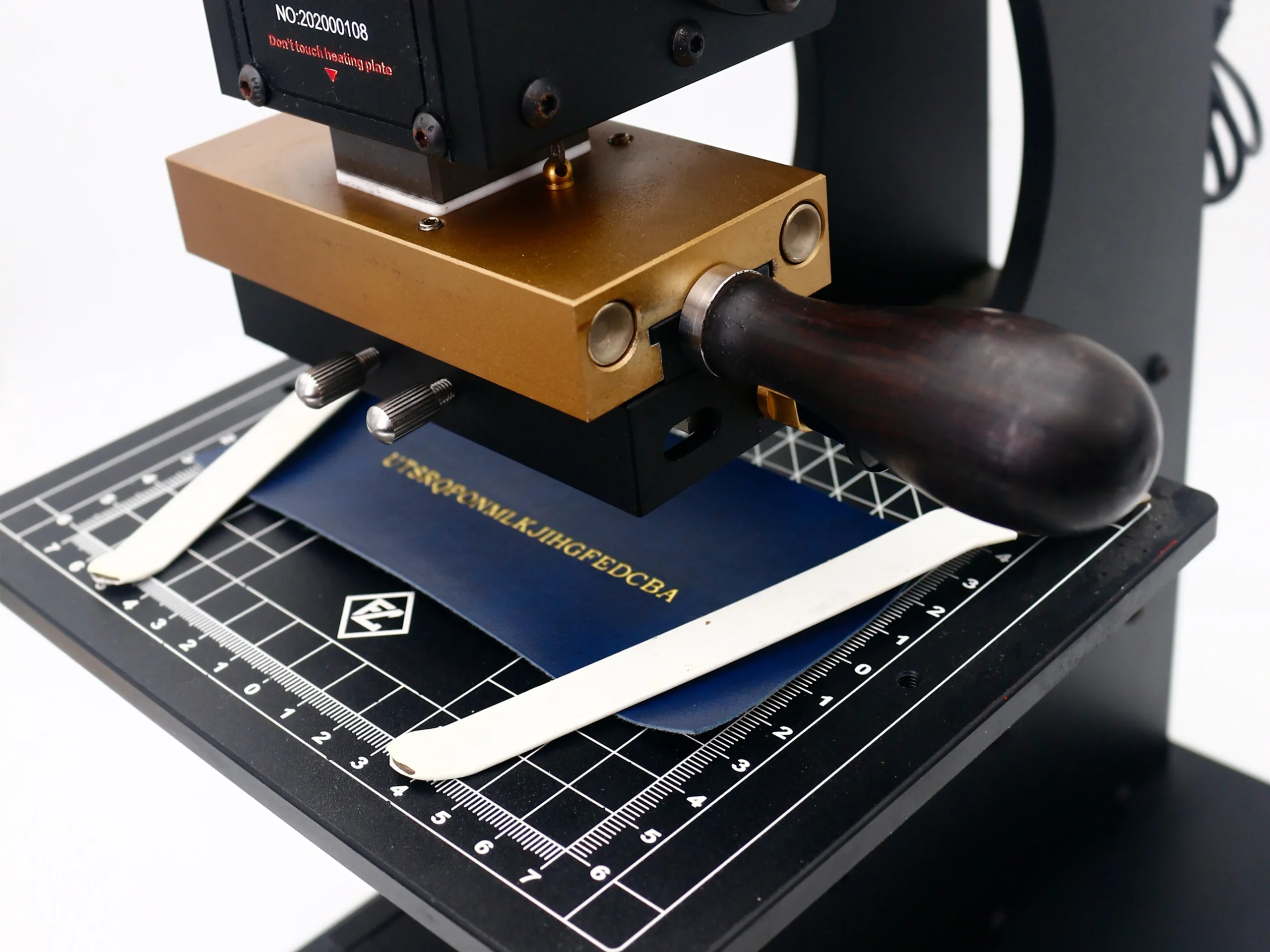 Close-up of ZHENGFEI WT-90XTS brass heating head stamping gold letters on blue leather.