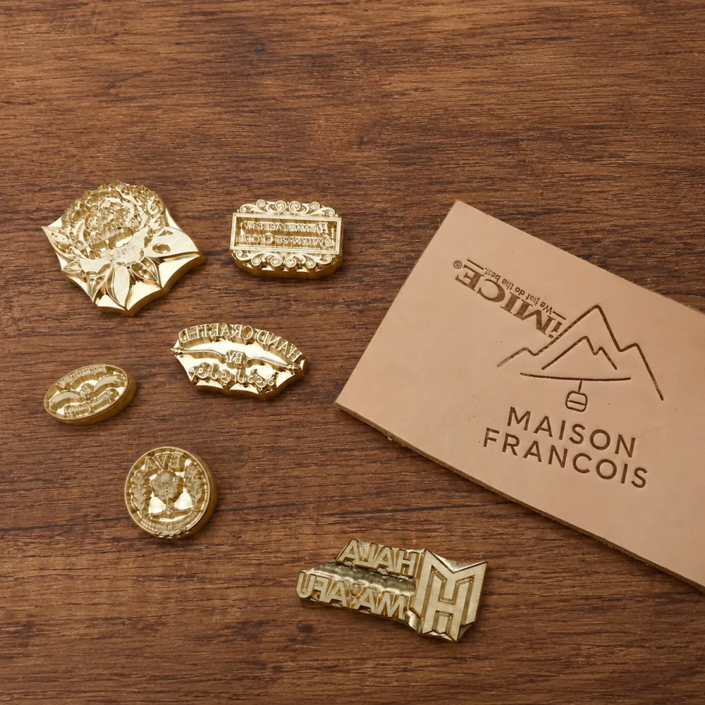 Landscape, workshop, floral industrial graphic custom brass stamp assortment laid on dark stained wooden table with dried eucalyptus styling.