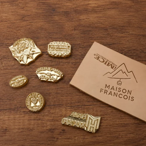 Landscape, workshop, floral industrial graphic custom brass stamp assortment laid on dark stained wooden table with dried eucalyptus styling.