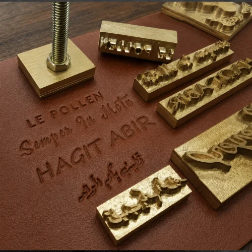 Latin & Arabic script brass text dies paired with blind embossed finished brown leather sample showing clear multi-language stamping results.