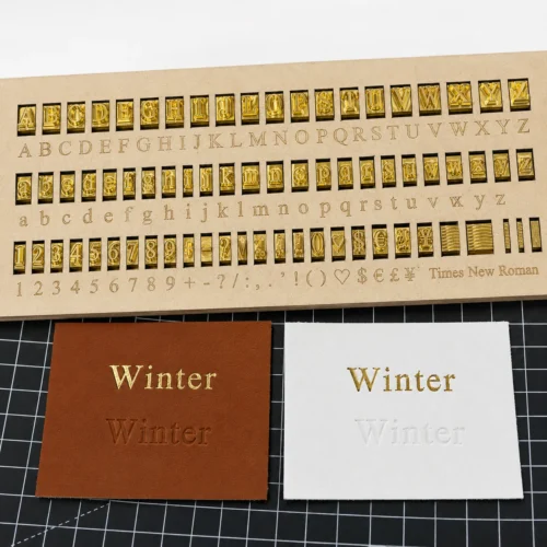 Times New Roman serif brass letters showing gold foil stamping and blind embossing on leather and paper
