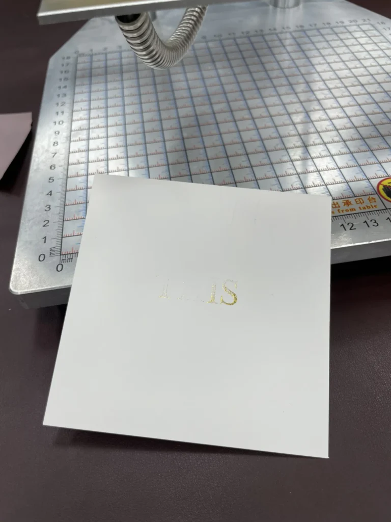 WT-90SK test at 90°C showing incomplete gold foil lettering on glossy cardstock