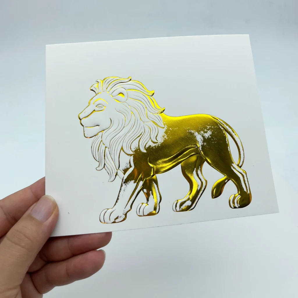 WT-QY300 hot stamping machine gold lion relief foil sample on glossy cardstock, test at 100°C with incomplete foil transfer